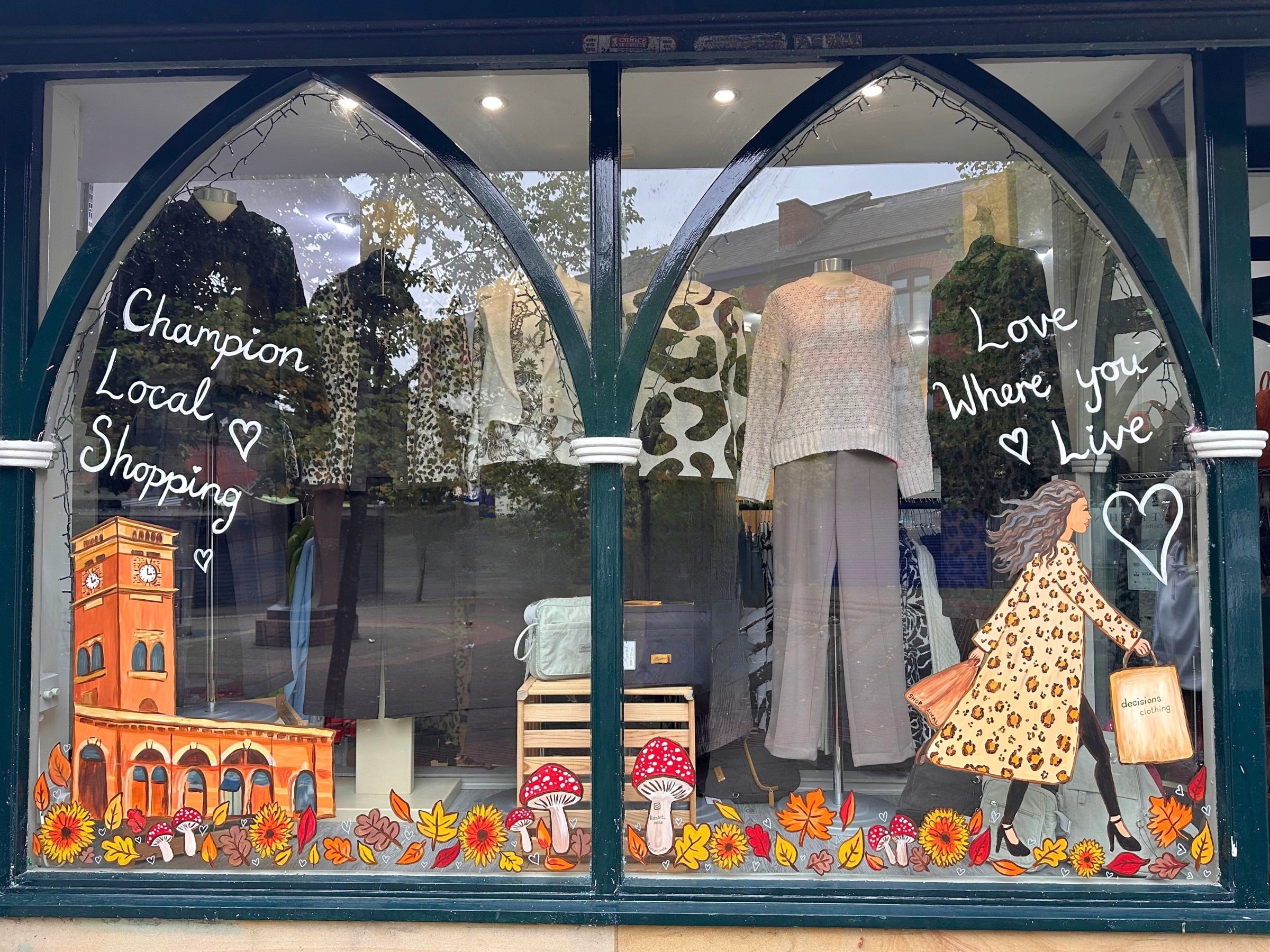 The autumn window display at Decisions Clothing, decorated with local landmarks, flowers and fashion illustrations